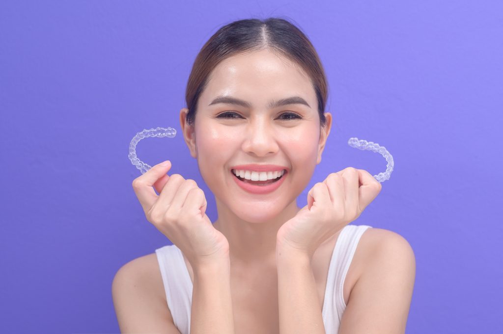 Young muslim woman holding Invisalign braces in studio, dental healthcare and Orthodontic concept..